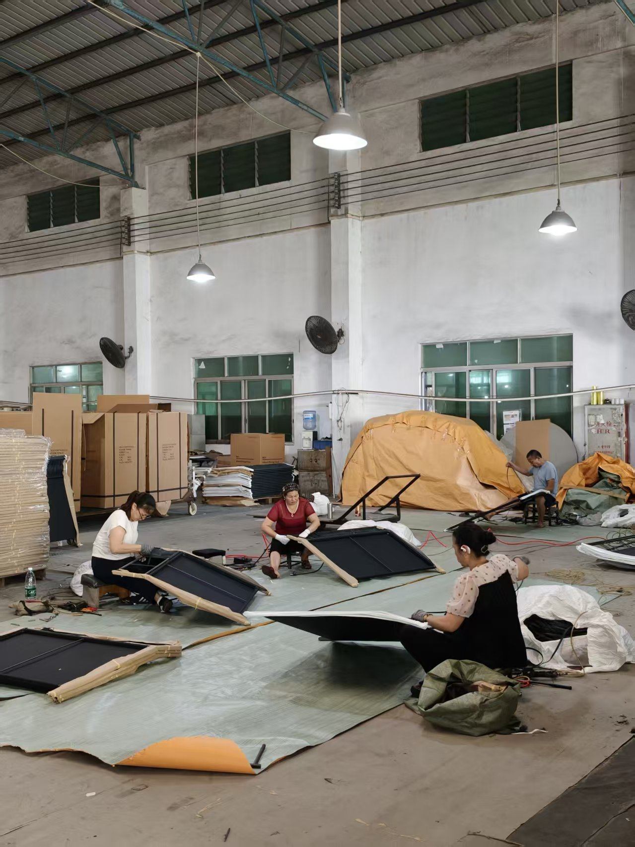 Workers assembling sling loungers on a furniture assembly line