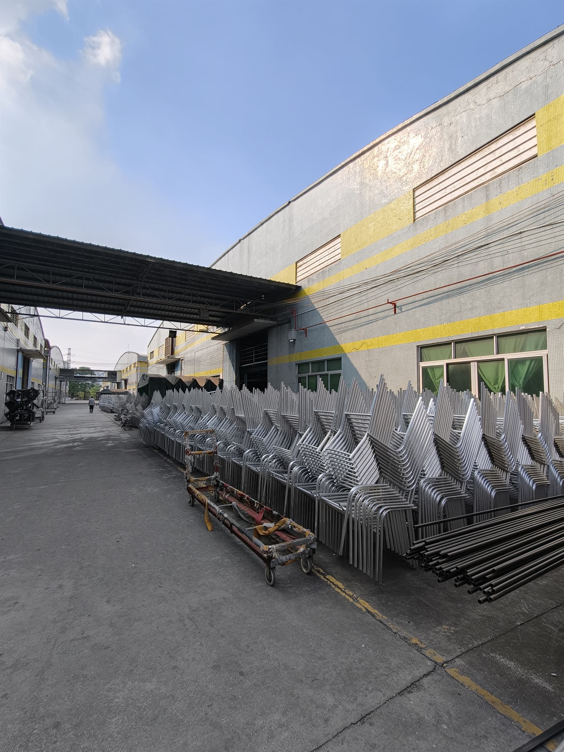 Rows of welded aluminum chair frames stacked outside the fabrication shop